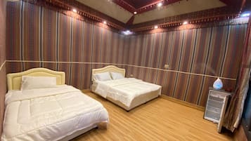 Habitación con dos camas, piso de madera y papel tapiz a rayas.