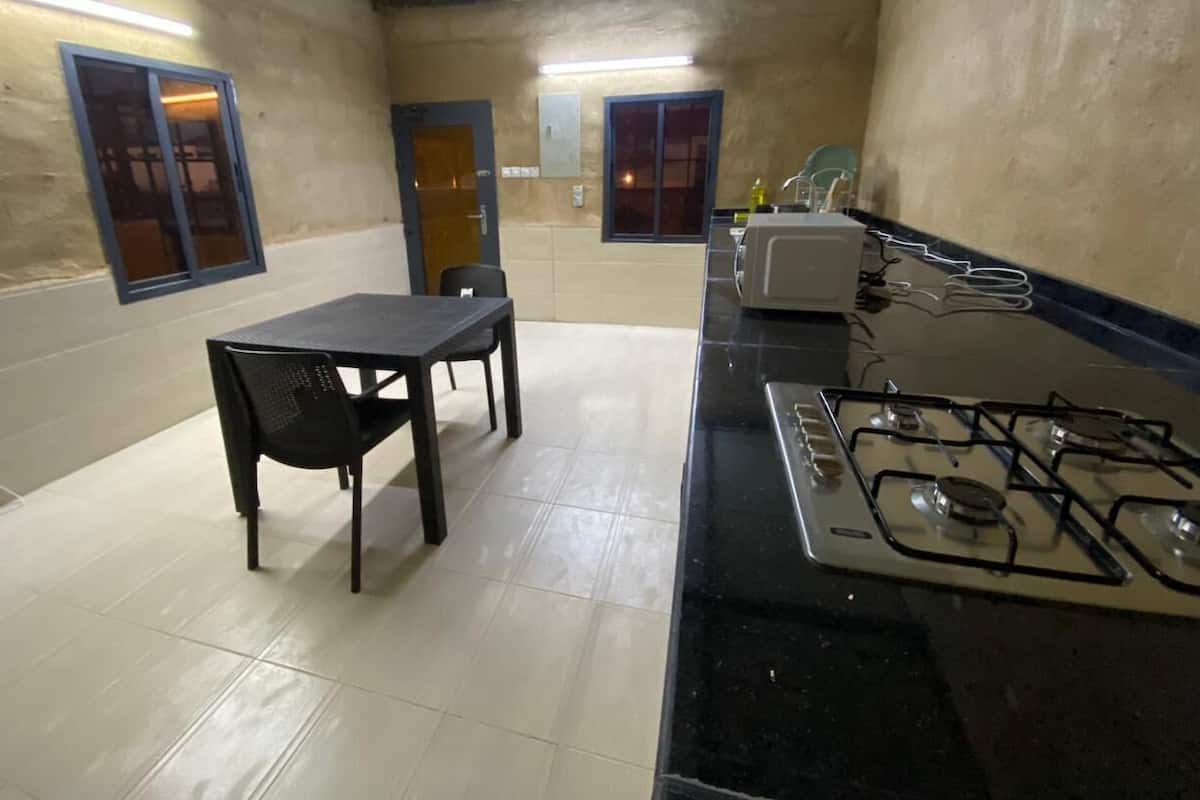 A compact kitchen with a gas stove, a small table, chairs, and a microwave.