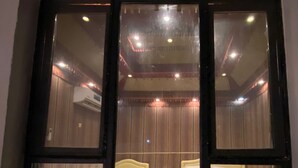 A room with two beds, wooden flooring, and a large window with curtains. - Sun Horizon Chalet (Nizwa)