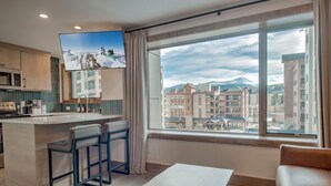 Una cucina moderna con un angolo bar, un'ampia finestra vista montagna e un'accogliente area salotto.