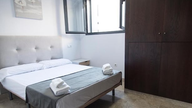 A bedroom with a bed, a nightstand, a wardrobe, and a window. - Night In Sevilla Duplex (Seville)