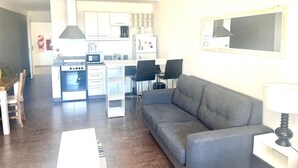 A compact living space with a kitchenette, a gray sofa, and a dining area.