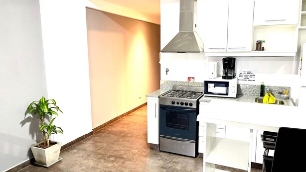 A modern kitchen with white cabinets, a gas stove, an oven, and a coffee maker.