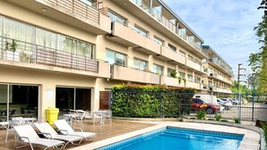 A hotel with a swimming pool, outdoor seating, and a multi-story building. - Alassio apartment, Pile view (Buenos Aires)