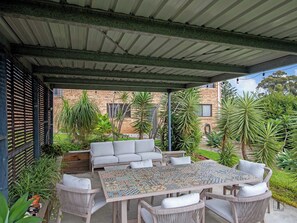 An outdoor patio area with a covered seating area, a patterned table, and surrounding greenery. - Pet-Friendly Home, Walk to Beach (Surf Beach)