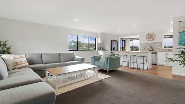 A modern living room with a grey sofa, a coffee table, and a bar area with stools.