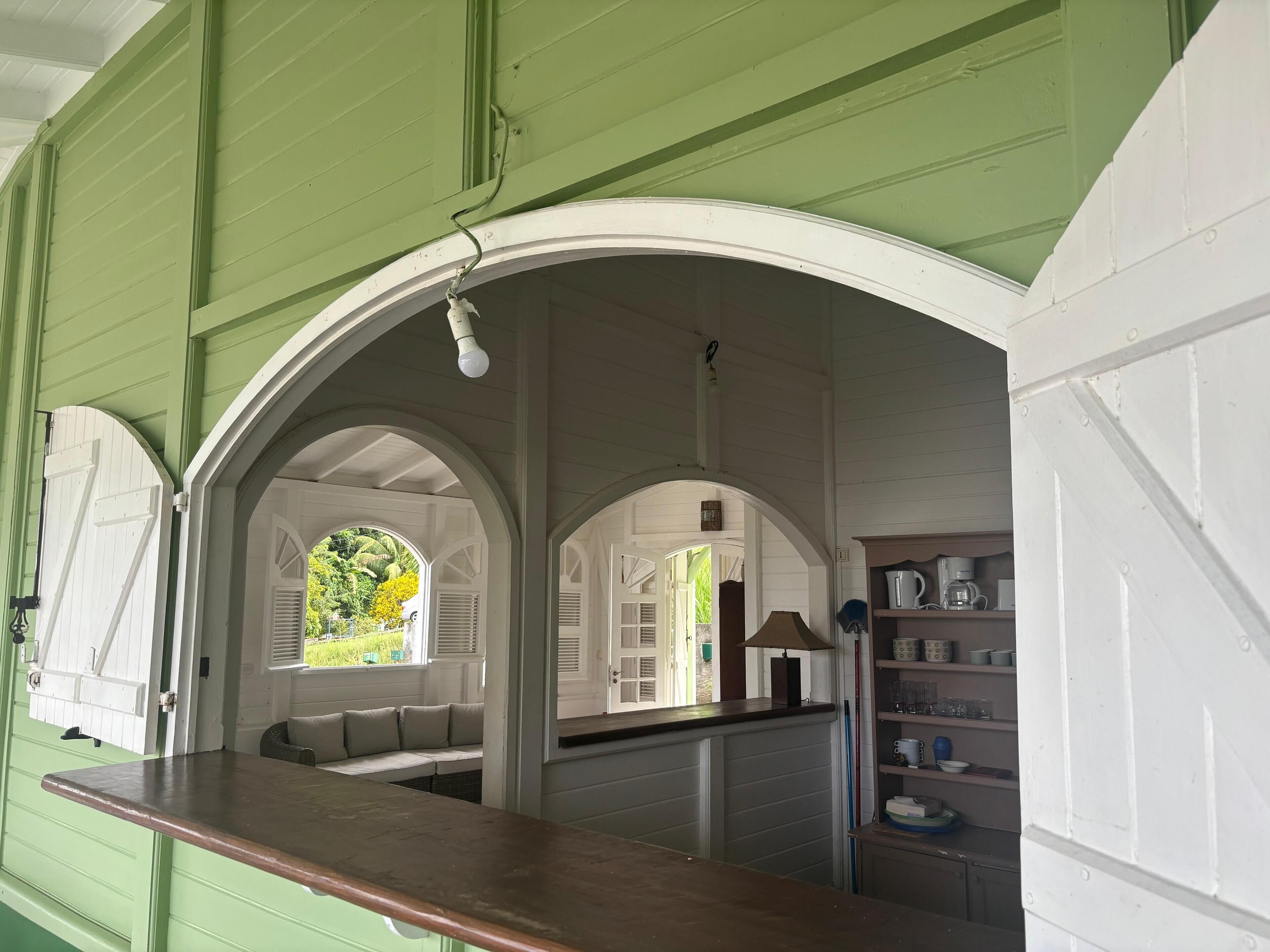 A kitchen with a wooden countertop, white cabinets, and a view of a garden through an arched window.