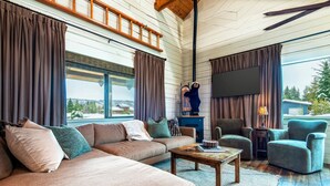 A cozy living room with a large sofa, armchairs, and a coffee table. There is a fireplace with a blue mantelpiece and a television mounted on the wall. - Upscale Designer Log Cabin, Cozy, Hot Tub, Firepit (Driggs)