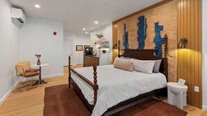 Une chambre à coucher avec un lit à baldaquin en bois, une petite table ronde, une chaise, une table de chevet et une lampe fixée au mur.