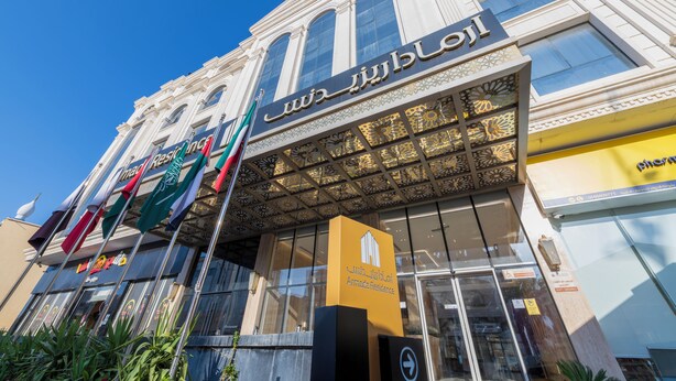 A hotel facade with a prominent sign, multiple flags, and a glass entrance. - Armada Residence Hotel (Taif)