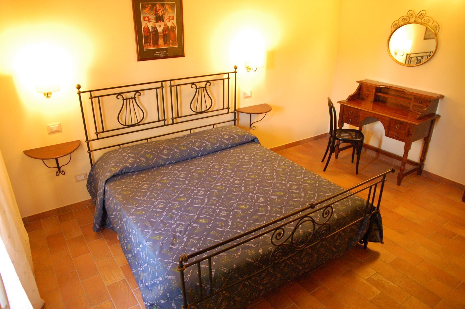 Ein Schlafzimmer mit einem Bett, einem Schreibtisch, einem Stuhl, einem Spiegel und Wandleuchten.