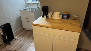 A compact kitchen with a wooden countertop, white cabinets, a sink, and a coffee maker. - Spacious 5BR Entire Home w/ Private Studio - Sleeps 10 (Pittsburgh)