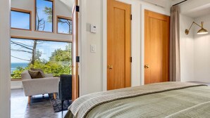 Un dormitorio con una cama grande, puertas de madera, vistas al exterior y un área de descanso con vistas.