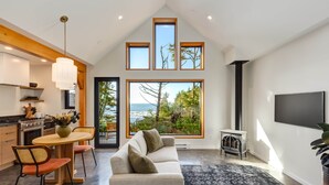 Una cocina moderna con comedor, un amplio ventanal con vistas al océano y un rincón acogedor con sofá y alfombra.