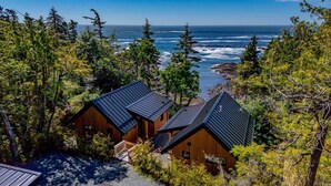 A coastal cabin complex with multiple wooden buildings, surrounded by dense forest and overlooking the ocean. - Fogged Inn Cove (Ucluelet)