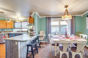 A kitchen with a central island, wooden cabinets, and a dining area with a table set for four. - Families Welcome! Home w/ Playground in Kingston (Kingston)