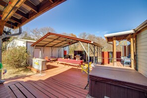 A covered outdoor deck with a picnic table, chairs, and a hot tub. - Families Welcome! Home w/ Playground in Kingston (Kingston)