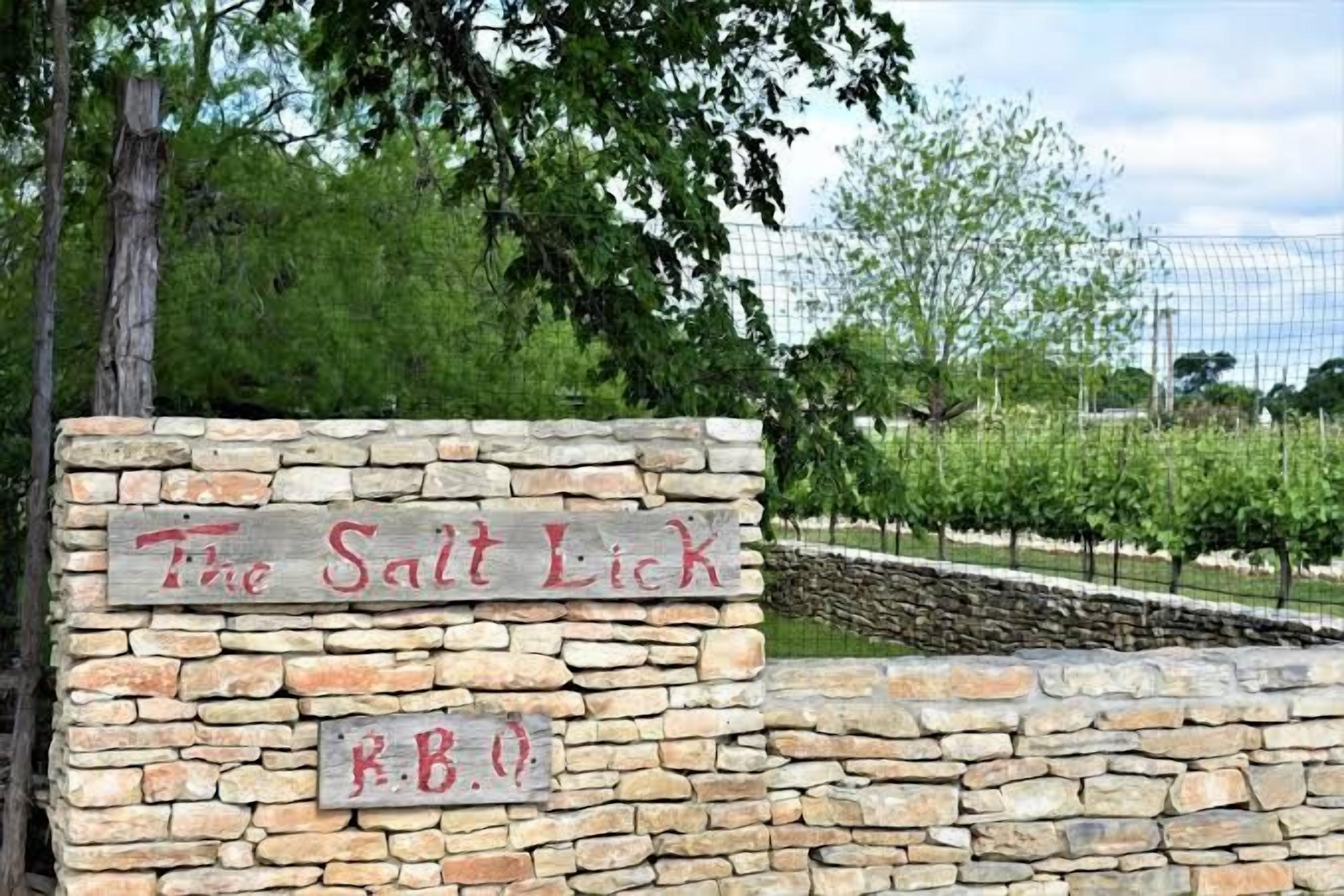 Een stenen muur met een bord waarop 'The Salt Lick' staat en een kleiner bord eronder met 'R.B.O'.