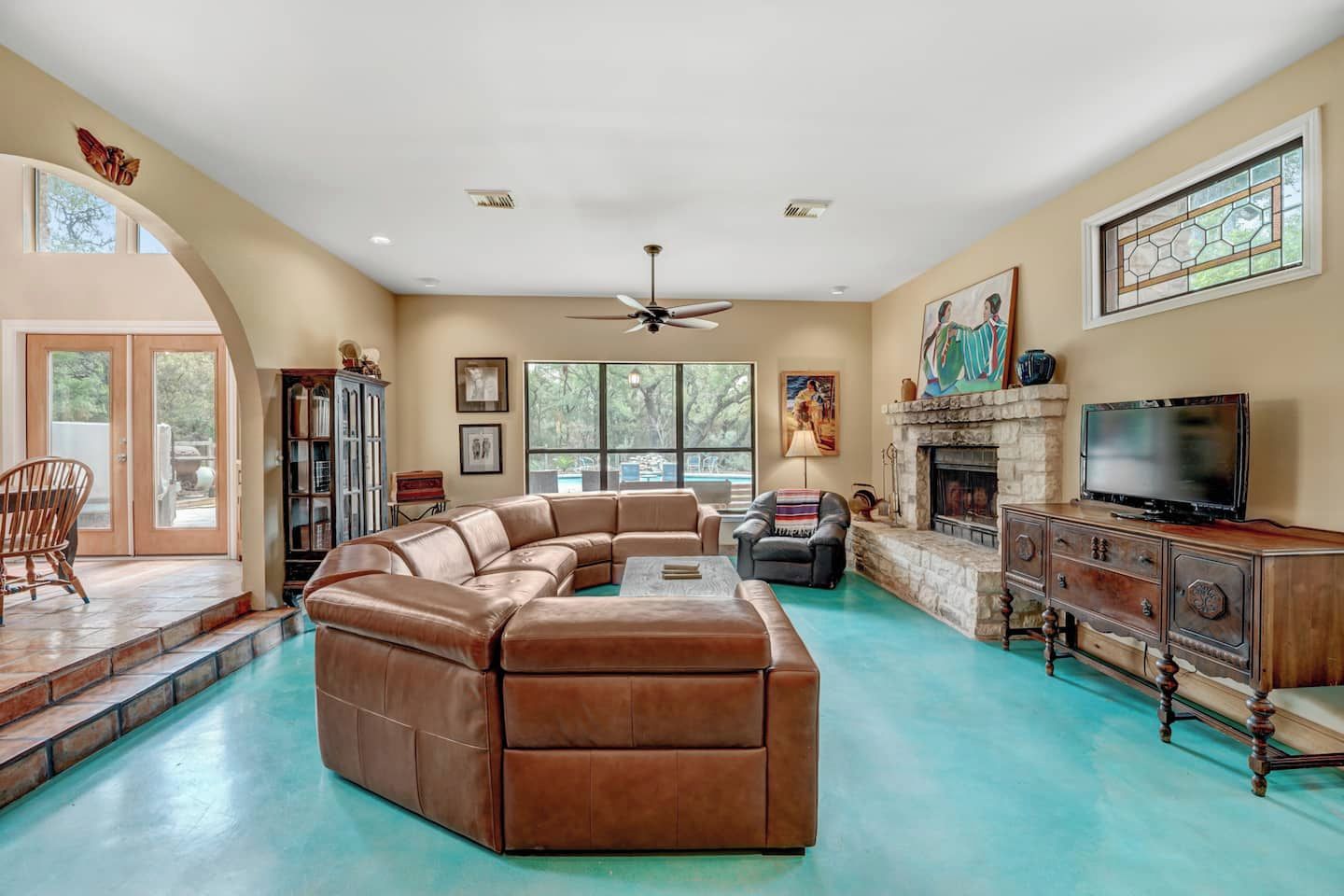 A spacious living room with a large sectional sofa, a fireplace, a television, and a stone fireplace surround.