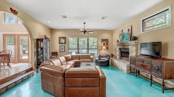 A spacious living room with a large sectional sofa, a fireplace, a television, and a stone fireplace surround.