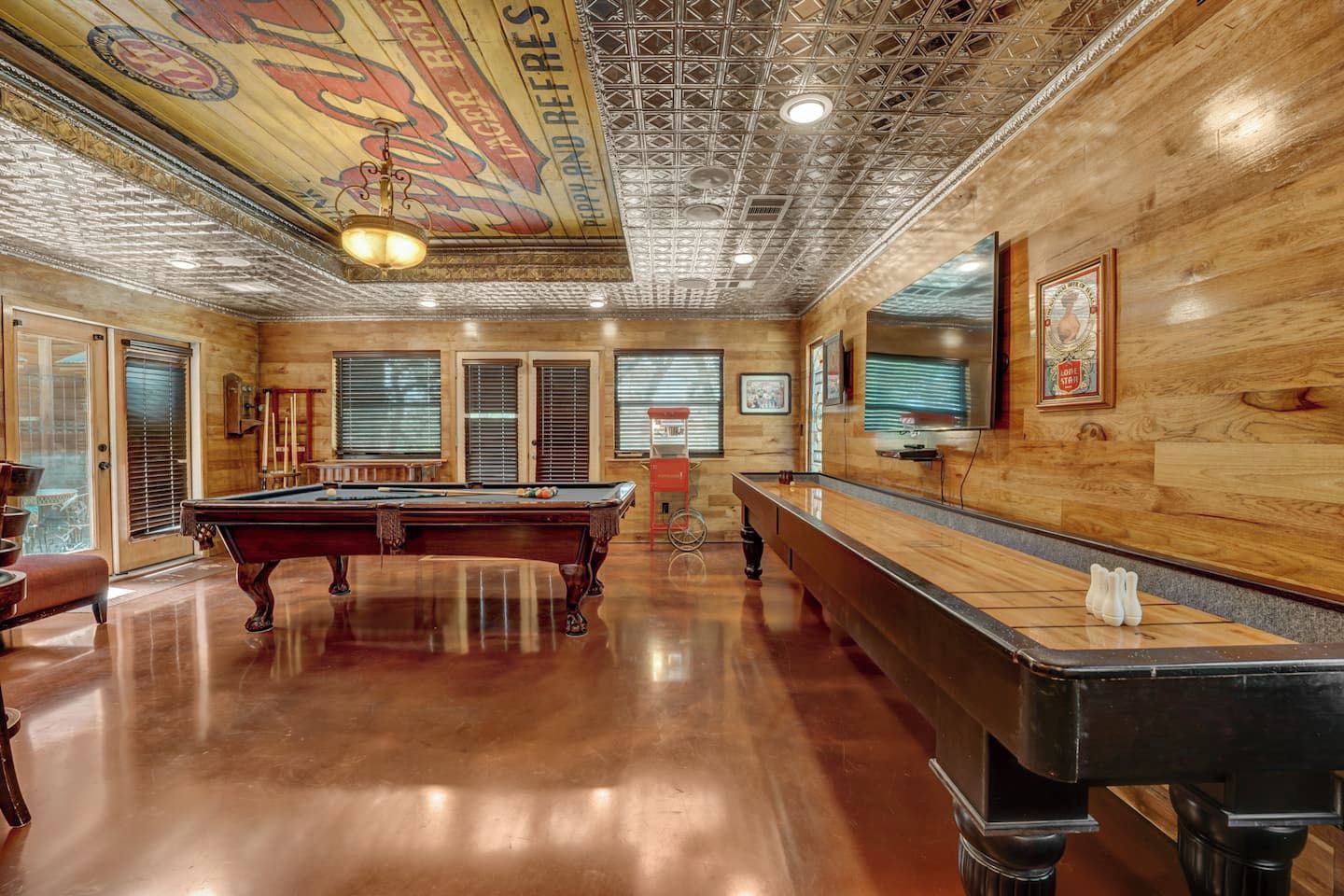 A pool table in a room with wooden walls and a ceiling with a geometric pattern.