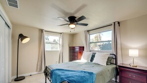 A bedroom with a bed, a ceiling fan, a dresser, and a floor lamp. - 2 Mi to Gulf! Pet-Friendly Home in New Port Richey (New Port Richey)