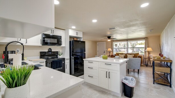 A modern kitchen with white cabinets, a black refrigerator, and a dining area with a table and chairs. - 2 Mi to Gulf! Pet-Friendly Home in New Port Richey (New Port Richey)