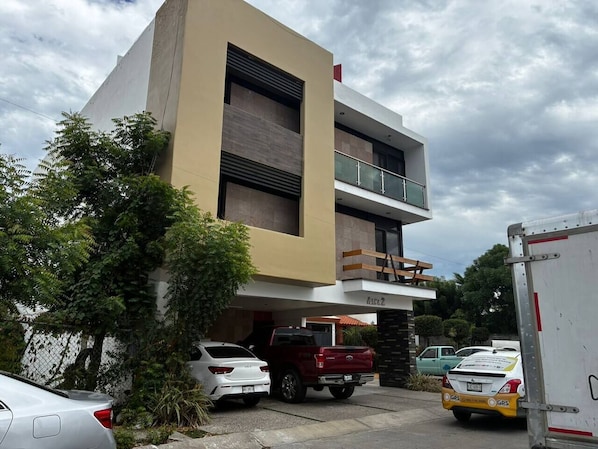 Un bâtiment moderne doté d’un toit plat, d’un balcon au deuxième étage et d’une entrée de garage.