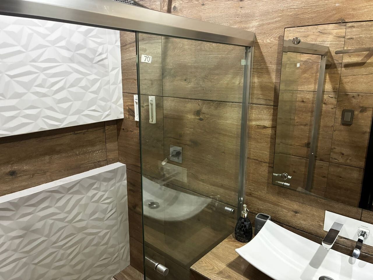Een badkamer met een douchecabine van glas, een wastafel en een spiegel.