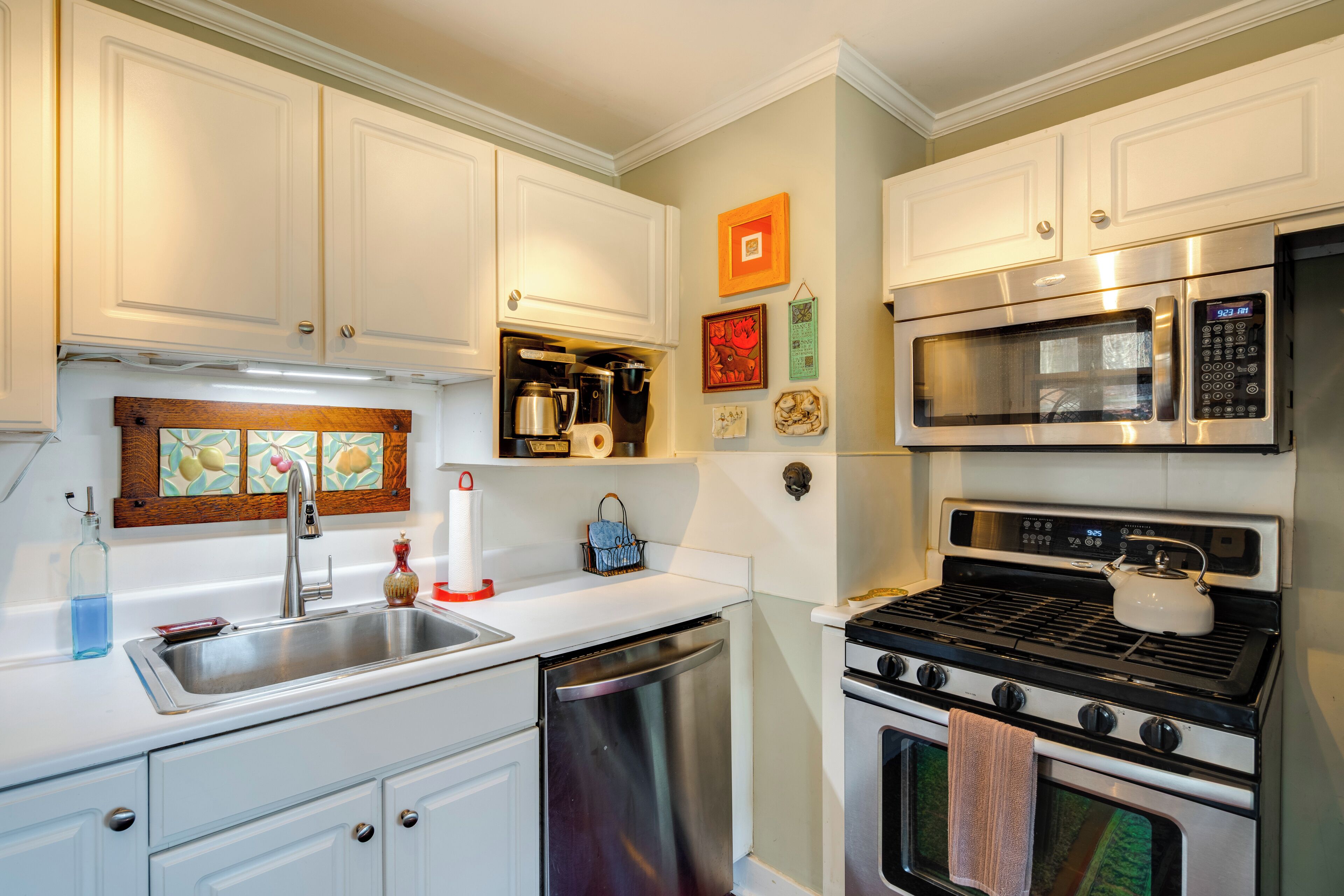 A modern kitchen with white cabinets, stainless steel appliances, and a dish rack.