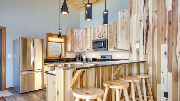 Eine Küche mit Holzausstattung, einem Edelstahlkühlschrank, einer Mikrowelle und einer Bar mit Hockern.