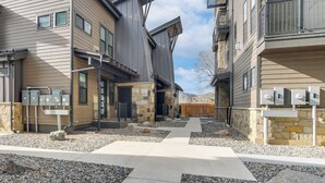 Un immeuble résidentiel à la façade en pierre, doté de nombreuses fenêtres et de boîtiers électriques extérieurs.