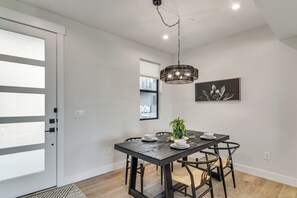 A dining area with a dark wooden table, white plates, and black chairs. There is a potted plant on the table, a hanging light fixture, and a framed picture on the wall. - 4 Mi to Granby Ranch: Gem w/ Balcony & Mtn Views! (Granby)