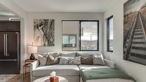 Un salon moderne avec un canapé d’angle, une table basse et des œuvres d’art accrochées aux murs.