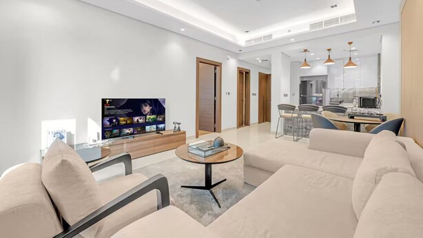 Una sala de estar moderna con un televisor de pantalla plana, una mesa redonda de centro y un sofá.
