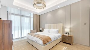 Una habitación de hotel moderna con una cama grande, mesitas de noche, un armario y una araña.