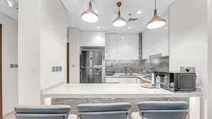 Una cocina moderna con armarios blancos, salpicadero de mármol y una isla central con taburetes de bar.