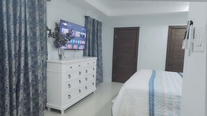 A bedroom with a bed, a dresser, a television, and a door.