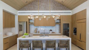 Una cocina moderna con una isla grande, armarios de madera y una lámpara colgante.