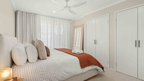 A bedroom with a bed, pillows, a bedside table, a ceiling fan, and a wardrobe. - 4 Bedrooms, Spacious Backyard, Fireplace, Walk to Beach (Callala Beach)