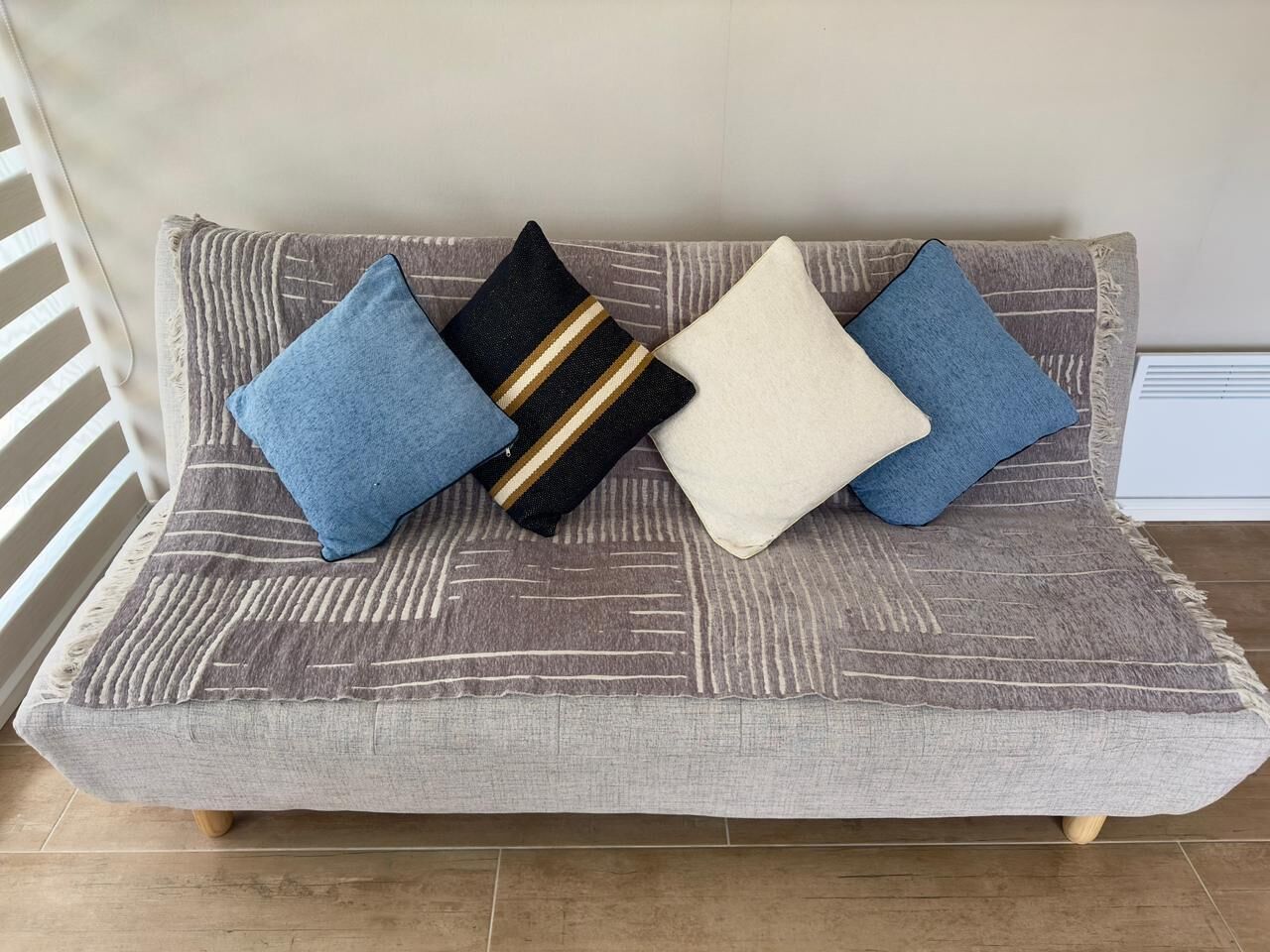 Un canapé gris à motifs texturés, agrémenté de trois coussins bleus, noirs et blancs.