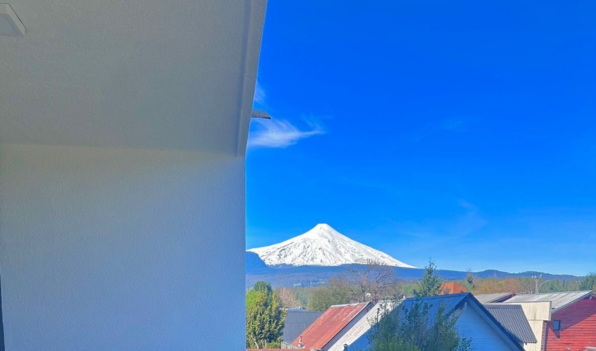 Blick auf den Fuji von einem Fenster mit Blick auf ein Wohngebiet, Häuser und einen klaren, blauen Himmel.