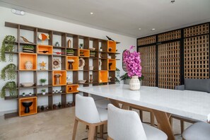 Un comedor con una mesa blanca, cuatro sillas y un revestimiento decorativo con estanterías.