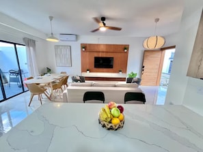 Eine moderne Küche mit Holzpaneelen als Rückwand, einem integrierten Fernseher und einem Essbereich mit einem Marmortisch und Stühlen.