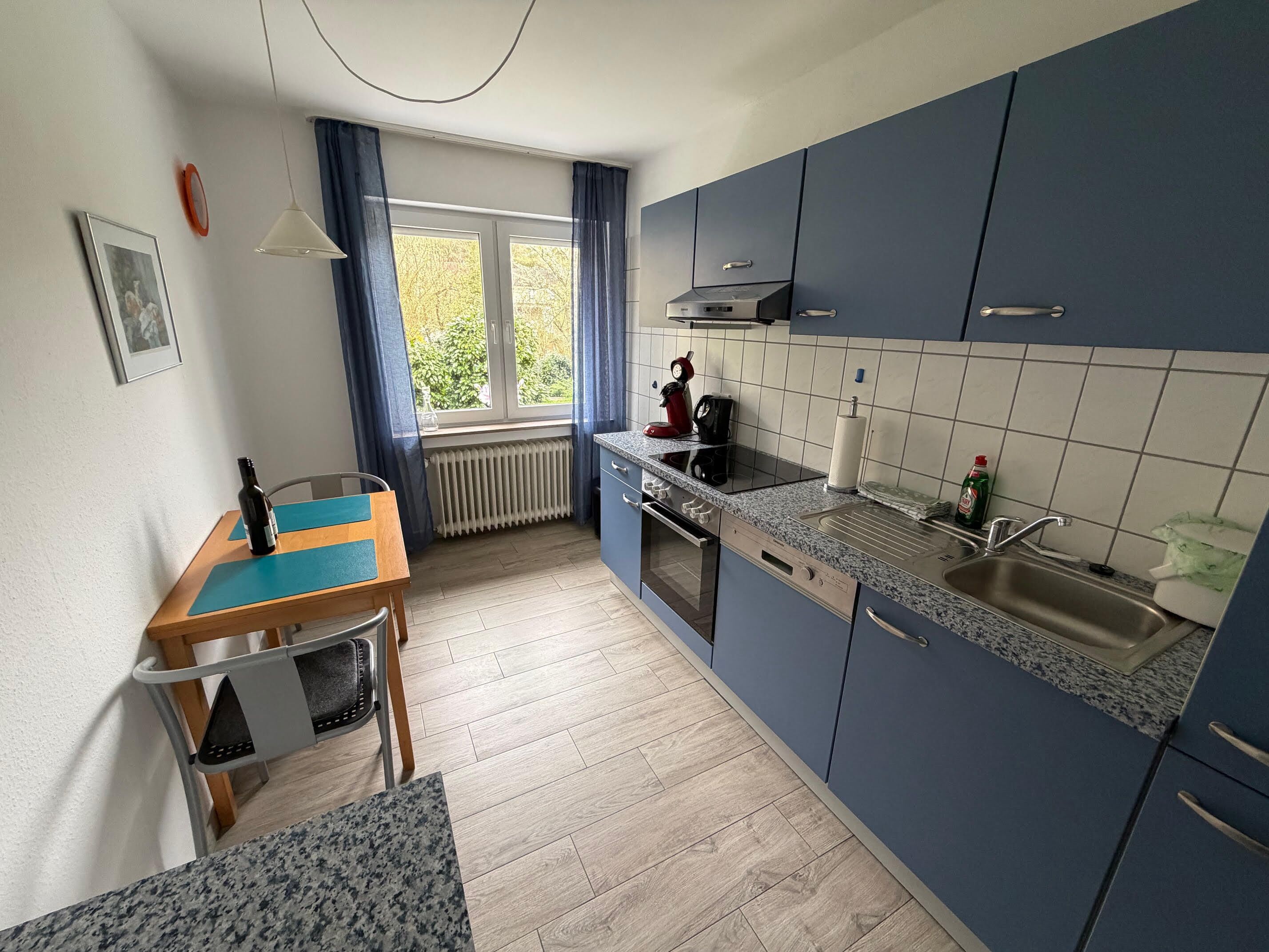 Une cuisine compacte avec un coin repas, comprenant une fenêtre, un radiateur, une cuisinière et un évier.