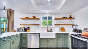 A modern kitchen with green cabinets, a white countertop, and a window with a view of greenery. - Boho Escape 3-bedroom house on 1.2 acres minutes from Joshua Tree National Park. (Yucca Valley)