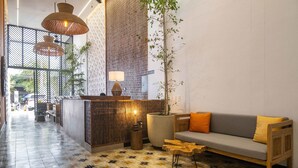 Un espace d’accueil avec un canapé, une lampe, une plante et un sol à motifs.