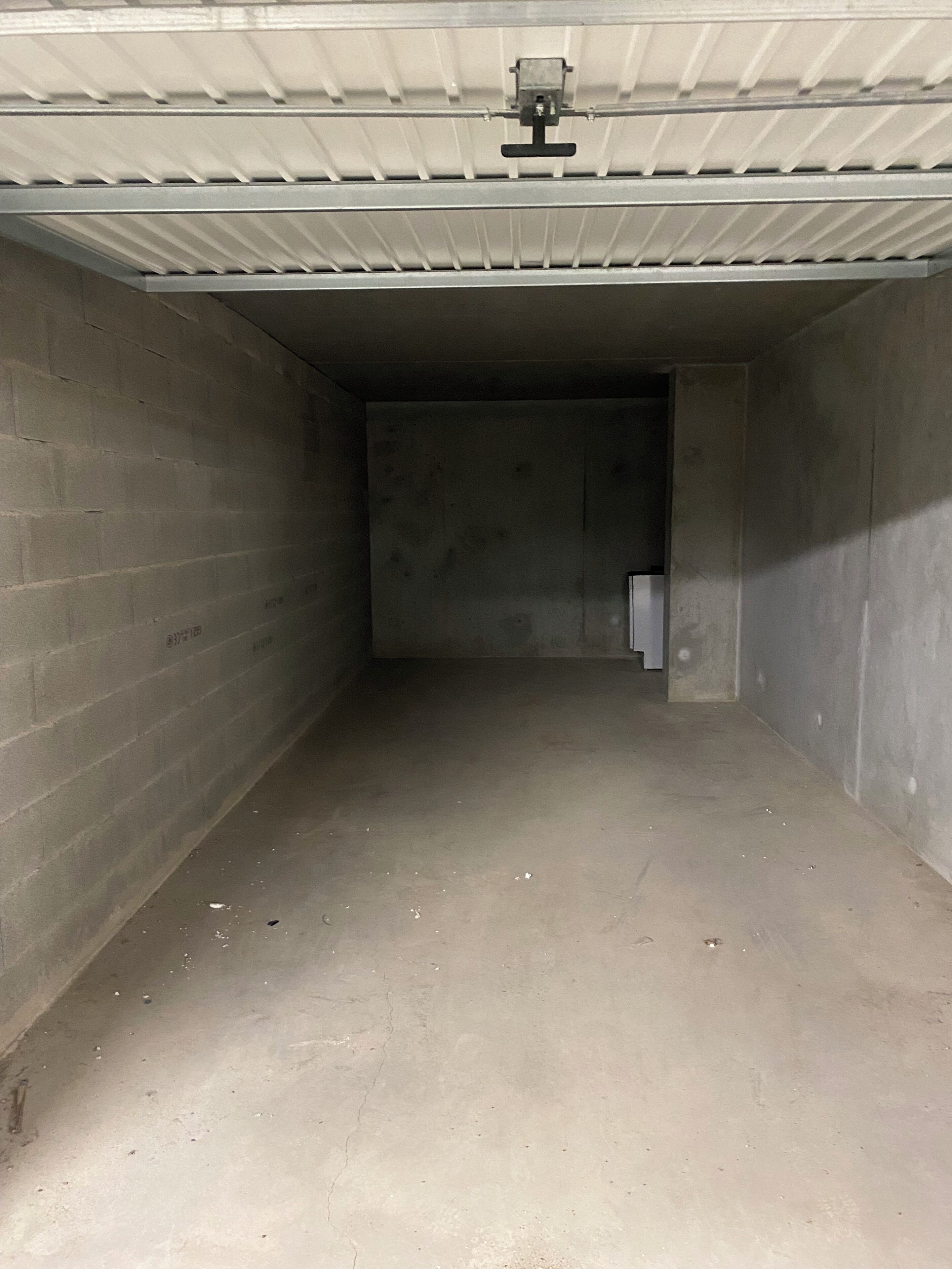 Un espacio interior estrecho e incompleto con paredes de concreto y techo metálico.