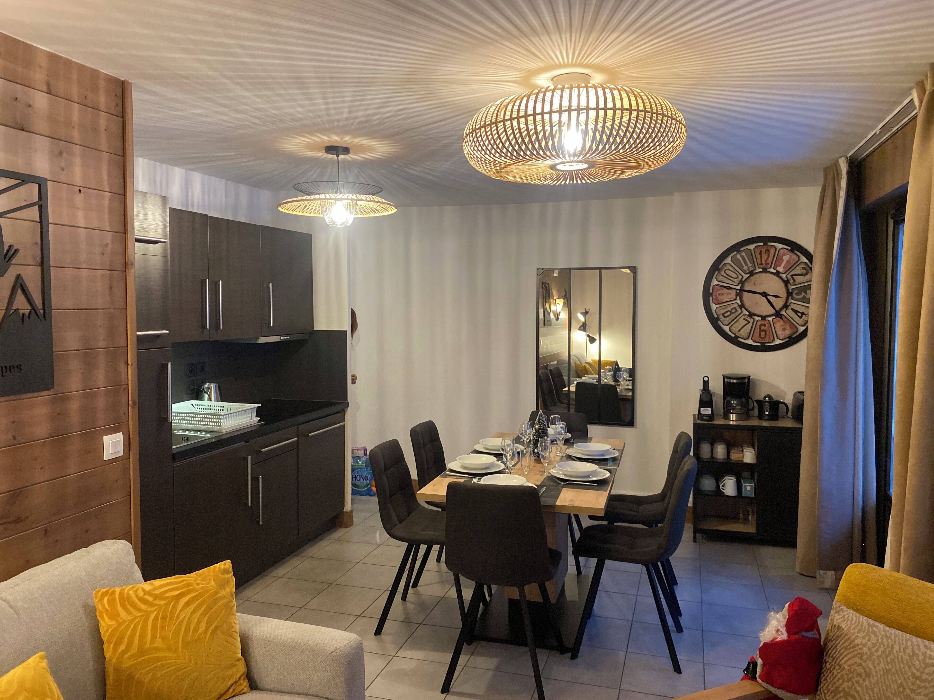Une cuisine moderne avec des meubles de couleur sombre et un coin repas comprenant une table et des chaises en bois.