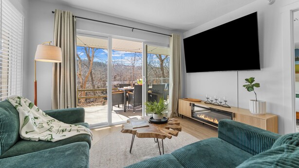 A modern living room with a green sofa, a coffee table, and a flat-screen TV mounted on the wall.